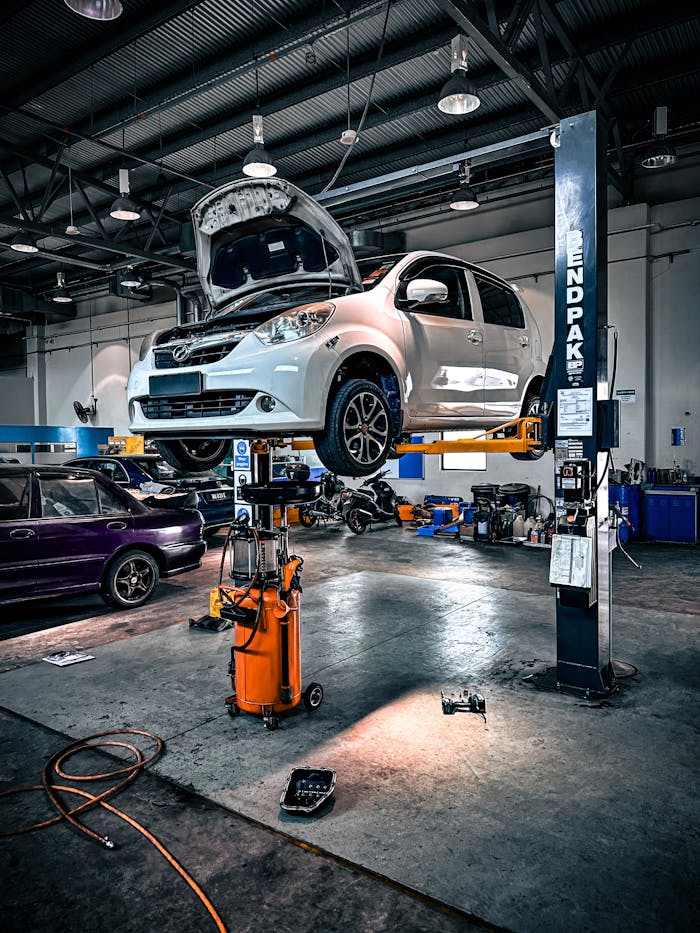 who-we-are A car is lifted on a hydraulic lift in a well-equipped auto repair shop.