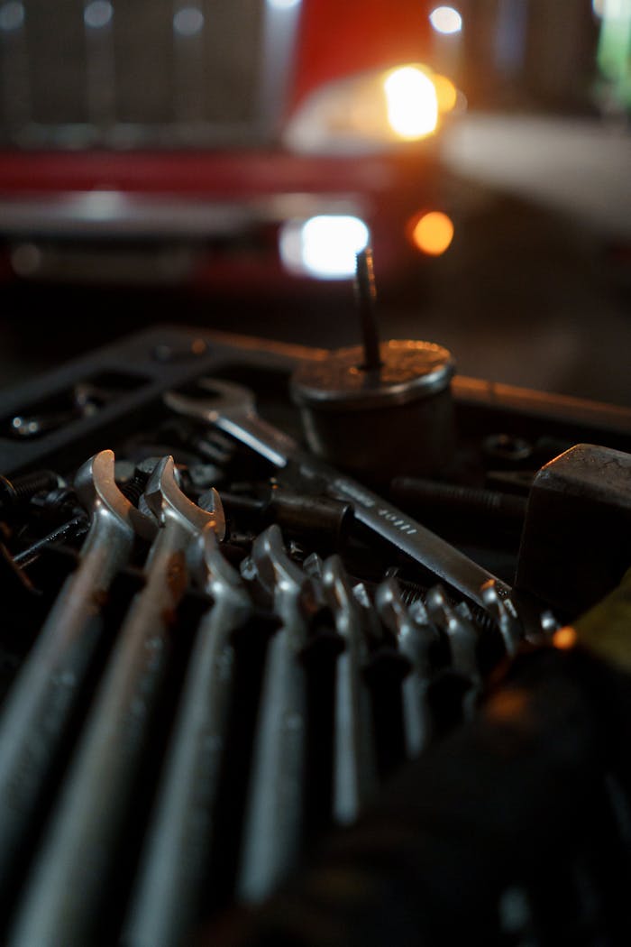 services-01 Close-up of mechanic's tools with classic car in the background, lit for night work ambiance.