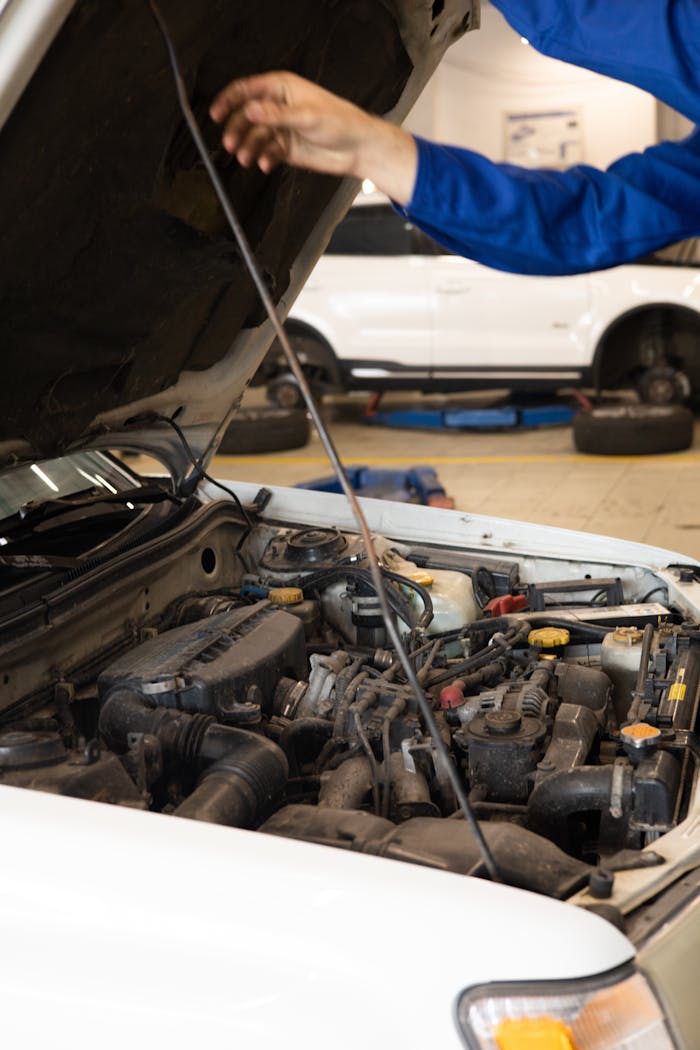 services-04 Close-up of mechanic inspecting car engine under open hood in an auto repair shop.