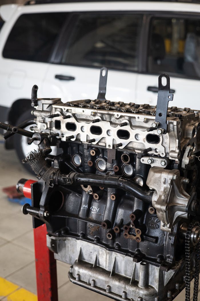 services-03 Detailed view of a car engine in an auto repair shop with a blurred vehicle in the background.